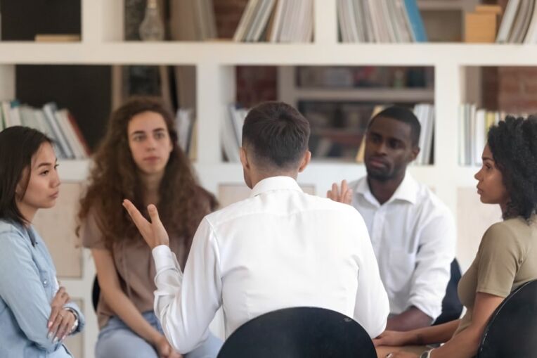 Rear,View,Man,Sharing,Problems,With,Diverse,Group,At,Therapy