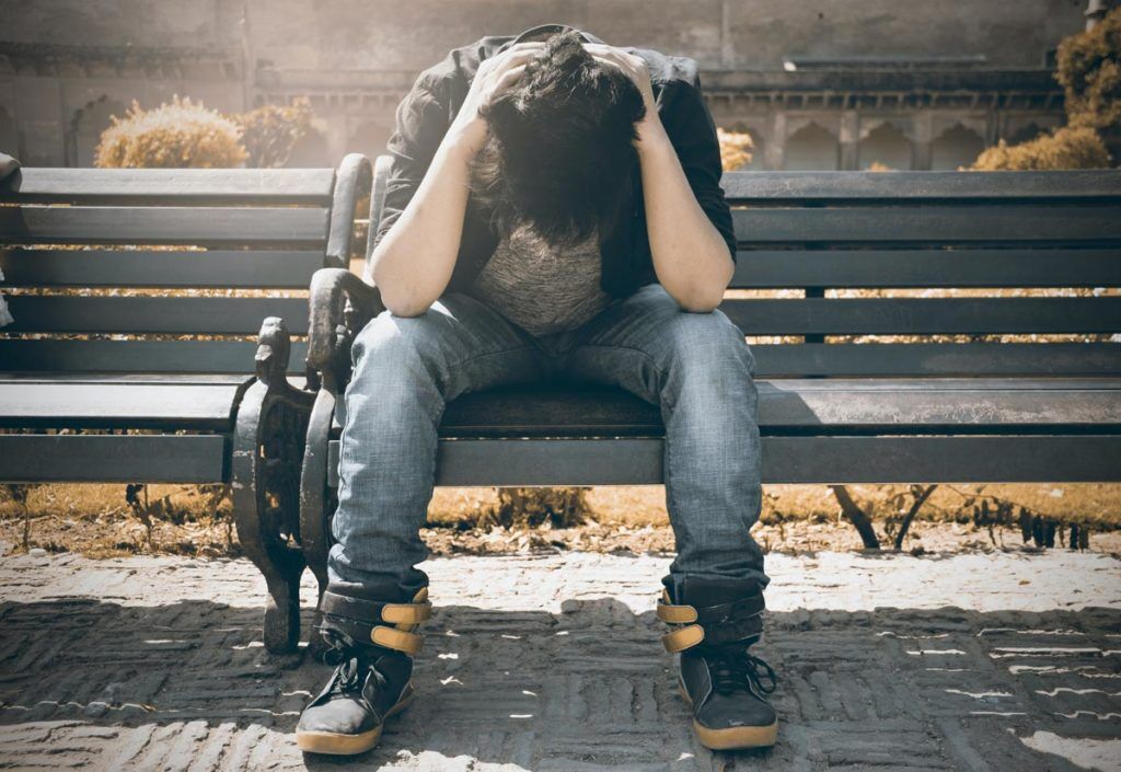 Man in Black Shirt and Gray Denim Pants Sitting on a bench having intrusive thoughts